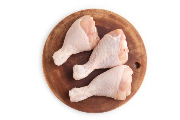 istock Raw chicken legs on a wooden cutting board isolated on white. Top view. 1643931448