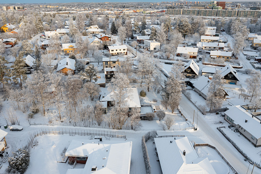 From the vantage point of a drone, the residential district emerges, gracefully draped in a pristine blanket of recent snow. The crisp whiteness contrasts with the structures below, painting a serene and picturesque winter landscape that captures the stillness and beauty of the season.