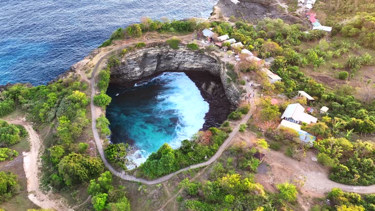 Aerial Drone Sunset Scene of Moving Wave at Broken Beach is one of the most famous sightseeing stops on Nusa Penida island in Bali. This is an amazing horseshoe-shaped circular cove formed in the rocks.