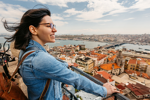 Young woman looking at view of the Galata Bridge in Istanbul, Turkey, at a high viewpoint.