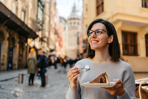 Young woman eating a San Sebastian cheesecake covered with chocolate.