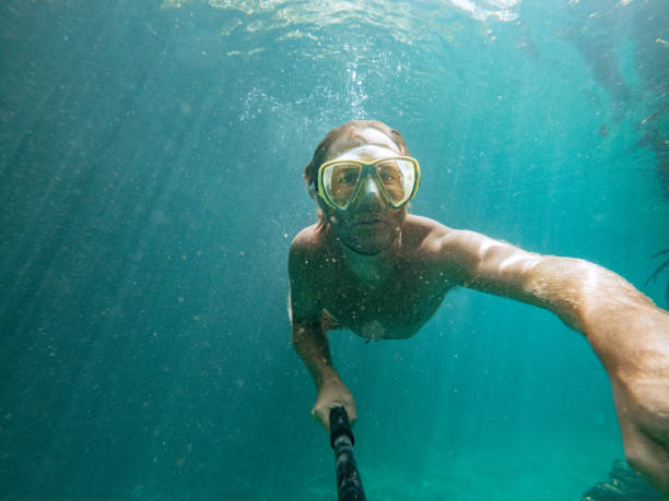 istock Man takes selfie underwater while swimming in a clear clean water 1643965417