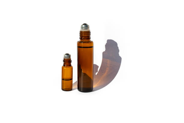 Roll on essential oil bottles on white background with sun light and strong shadows