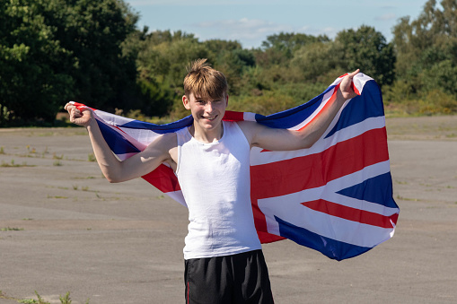 A happy and laughing teenage boy waving the Union Flag