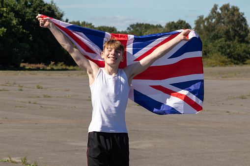 A happy and laughing teenage boy waving the Union Flag