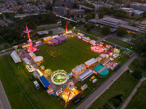 Fair during a summer sunset with illuminated fairground attractions in various colors in the park in Zwolle, Netherlands, during the summer fair.