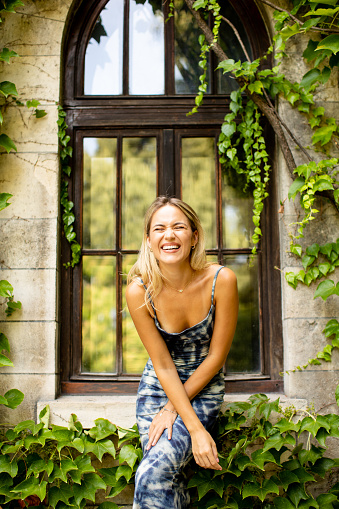 Pretty young woman by old house with ivy