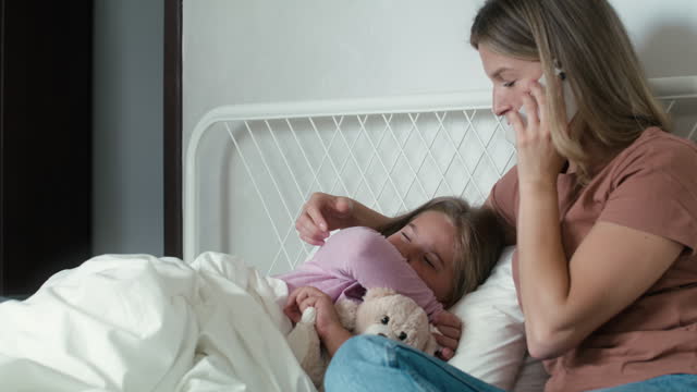 Mother calling a doctor while her daughter lying ill in bed. Shot with RED helium camera in 8K.