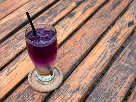 Close up a glass of fresh butterfly pea drink, Clitoria ternatea, on old wooden table.
