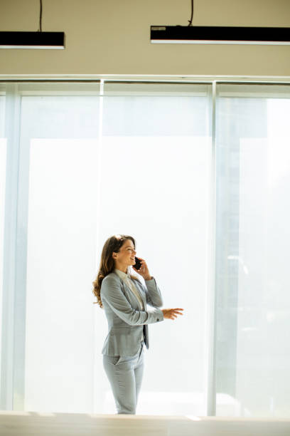 istock Young woman using mobile phone by the office window 1644006230