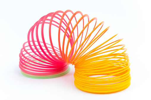 Rainbow colored wire spiral toy on white background