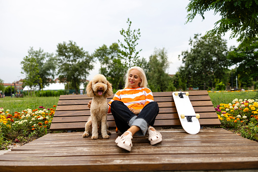 Mature adult happy woman enjoying with dog at skate park