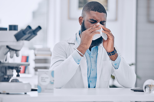 Scientist, man and sick nose in laboratory of cold, allergies and medical virus. African worker, science researcher and sneeze for health, allergy risk and tissue for disease, sinusitis and influenza