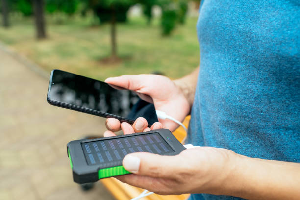 istock Man charging smartphone with solar panel in a city in a sunny summer day. Sustainable lifestyle, solar energy, ecological alternative energy and ecology concepts. 1644063392