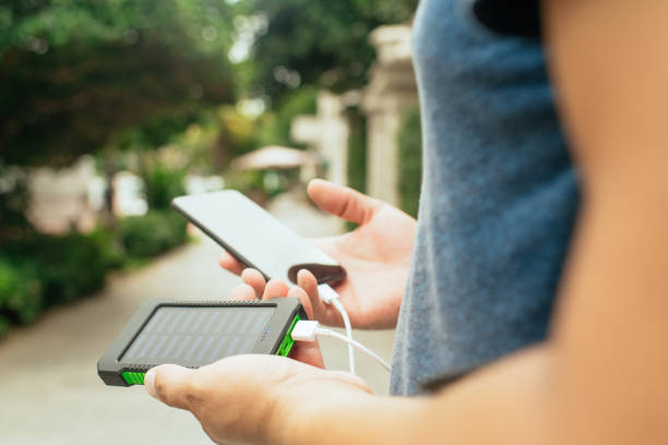 istock Man charging smartphone with solar panel in a city in a sunny summer day. Sustainable lifestyle, solar energy, ecological alternative energy and ecology concepts. 1644063401