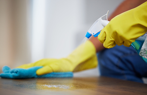 Cleaning spray, wipe and hands of a person on a table for dust, housekeeping service and morning routine. Dirt, hygiene and cleaner with liquid detergent for a sanitary counter for a fresh home