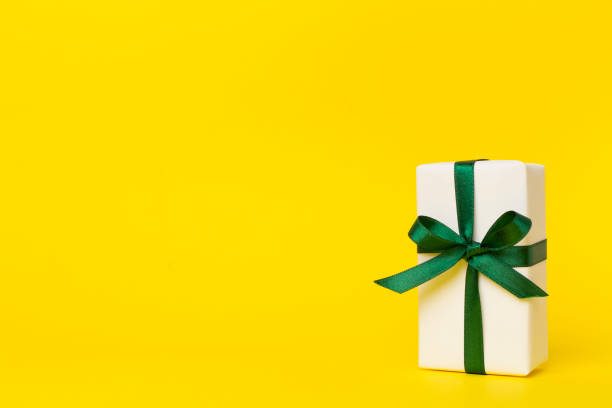 Gift box with green ribbon bow on color background