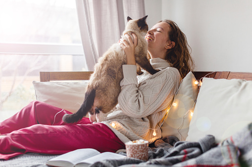 Cold autumn or winter weekend Young woman with cat drinking warm cocoa or coffee. Lazy day on the couch. Cosy scene, cozy home concept