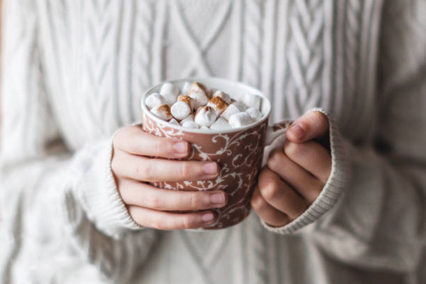istock Girl in a cozy knitted sweater drinking coffee from a mug 1644107561