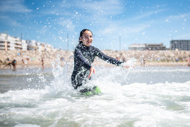 istock girl with neopren wetsuite splashing in the breakers 1644121321