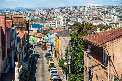 Valparaiso, Chile - 12th November 2022: Looking down Cepilla, one of the steep streets with brightly painted buildings in the Cerro Alegre area of Valparaíso, Chile. The view leads to Valparaíso Bay and the skyscrapers of Viña del Mar Cerro Alegre is a residential area which is also very popular with tourists.