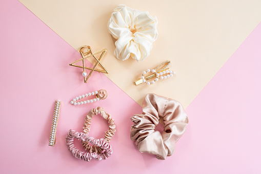Collection of trendy silk elastic band scrunchies and pearl hair clips on color background. Diy accessories and hairstyles concept, luxury color