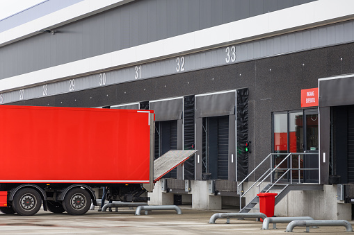 Loading docks at a distribution center in the Neterlands. A red truck is parked in front of the dock, ready to load it.