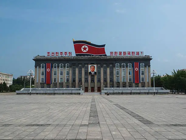 Pyongyang, North Korea – July 27, 2011: The Kim Il-Sung Square is named after the founding leader of the DPRK. It opened in August 1954. The square is located on the west bank of the Taedong River, directly opposite of the Juche Tower. The square is the common gathering place for North Korea's massive military parades. The marks on the ground serve to position the soldiers and units during these parades. 
