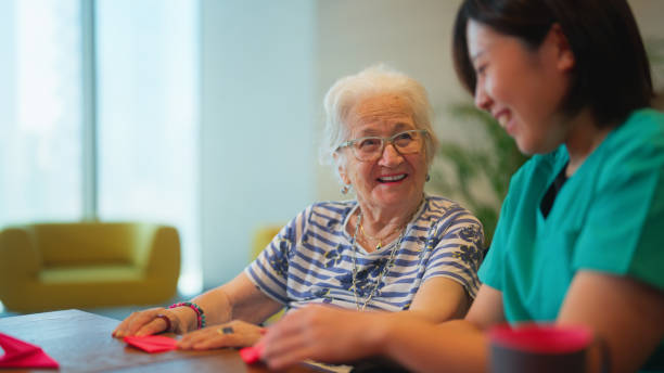 mujer mayor aprendiendo a hacer origami como para la actividad de fisioterapia - care community 80 plus years cheerful fotografías e imágenes de stock