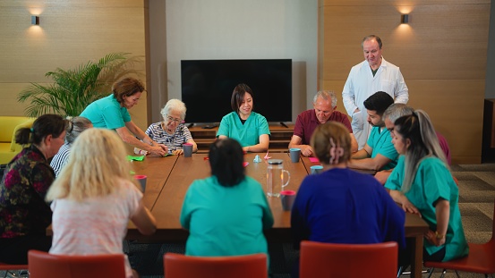 A group of senior people are enjoying learning and doing origami in nursing home.