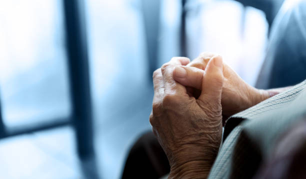 Old woman hands clasped praying stock photo