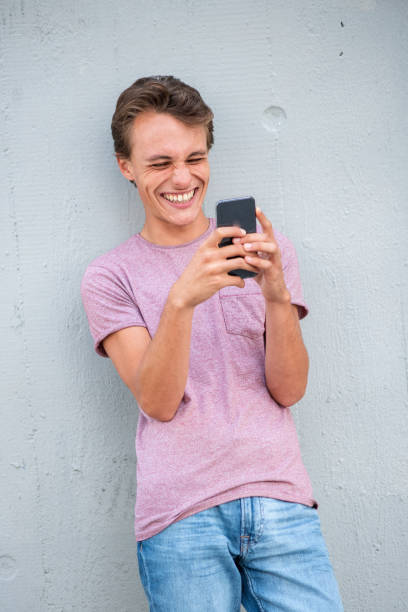 istock Handsome young man leaning to wall using cellphone and smiling 1644227636
