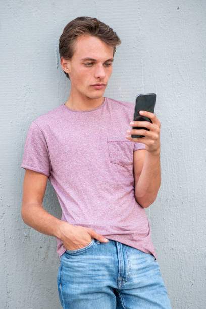 istock Handsome young man with mobile phone leaning to wall 1644228151