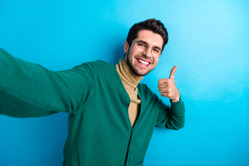 Photo of cheerful nice person toothy smile make selfie demonstrate thumb up approval isolated on blue color background.