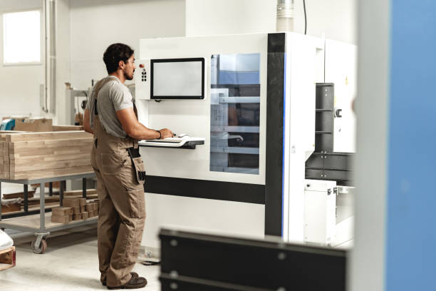 istock Young carpenter operating machine for wood processing at a furniture factory 1644244095