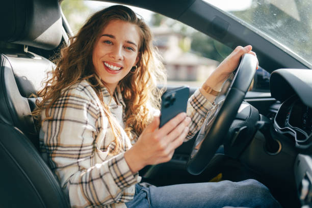 istock Young woman texting on her smartphone while driving a car 1644244618