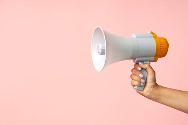 istock Megaphone loudspeaker in woman hands on pink background 1644252238