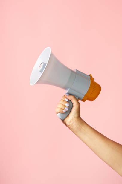 istock Megaphone loudspeaker in woman hands on pink background 1644252369