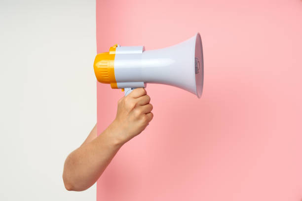 istock Megaphone loudspeaker in woman hands on pink background 1644252371