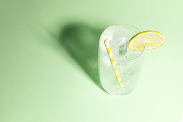 istock Cold glass full of ice with a lime slice on green background with cast shadow. 1644255291
