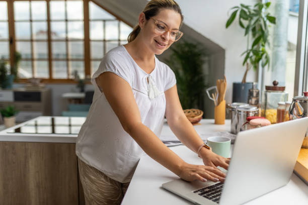 istock Woman using a laptop in the kitchen 1644265253
