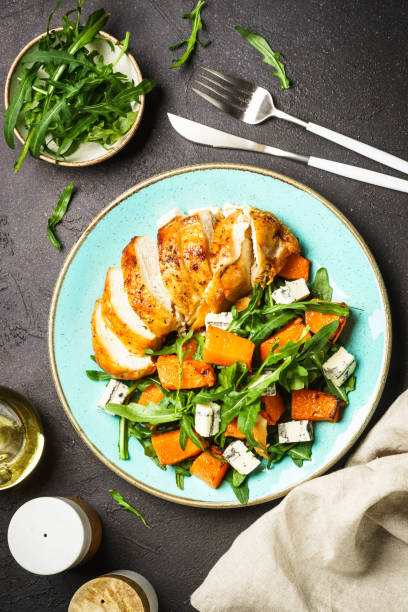 istock Chicken salad with pumpkin and arugula at black. 1644275322