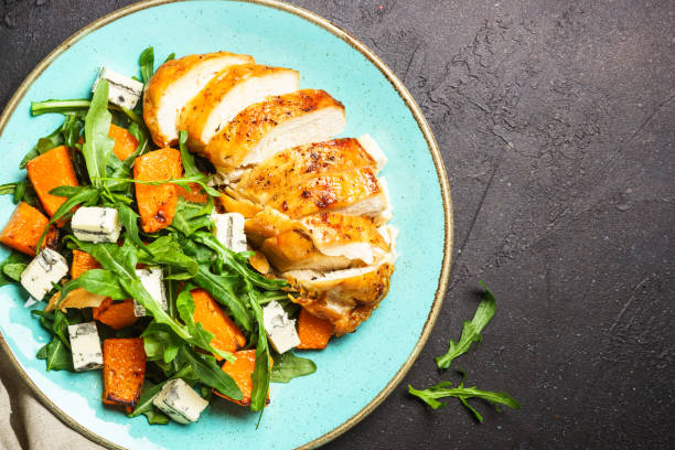 istock Chicken salad with pumpkin and arugula at black. 1644275323