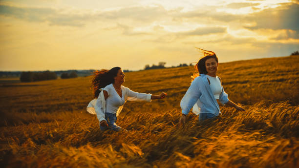 istock Cheerful female friends playing in field at sunset during vacation 1644284792