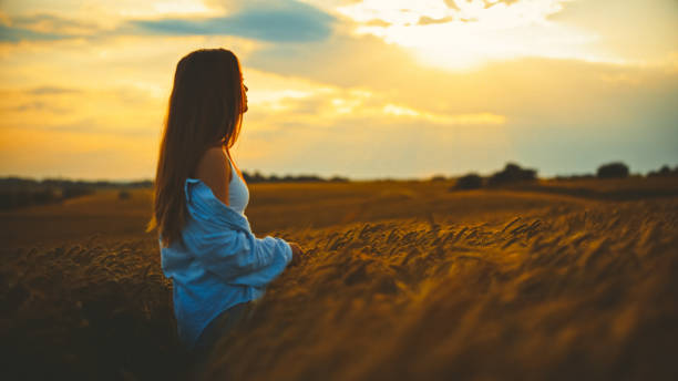 istock Young woman amidst crops enjoying sunset view 1644285843