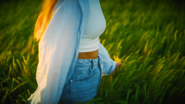 Midsection of young woman walking amidst crops enjoying freedom during vacation