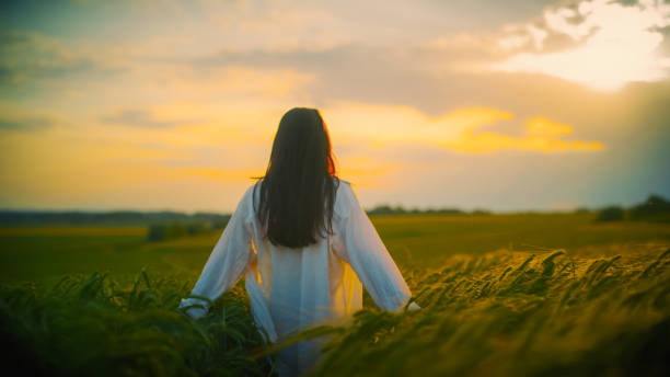 istock Woman amidst crops in field enjoying sunset 1644286543