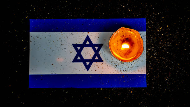 istock Israeli flag and candles burning above it, Holocaust memory day 1644307250
