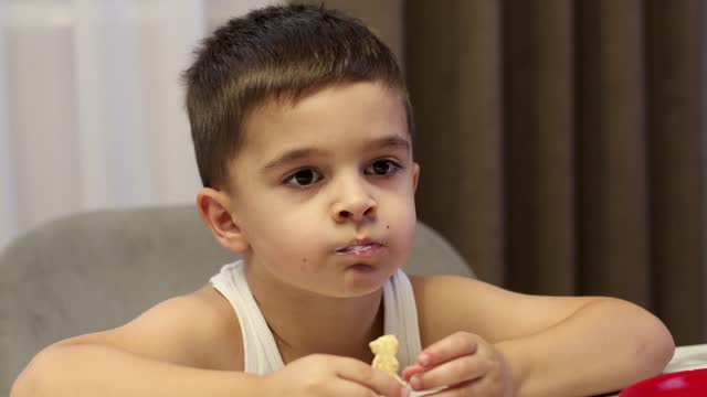 Cute little toddler boy eating at home