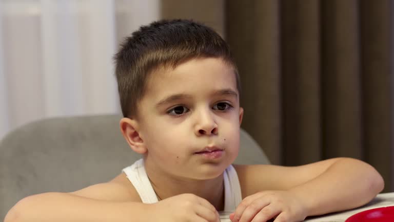 Cute little toddler boy eating at home